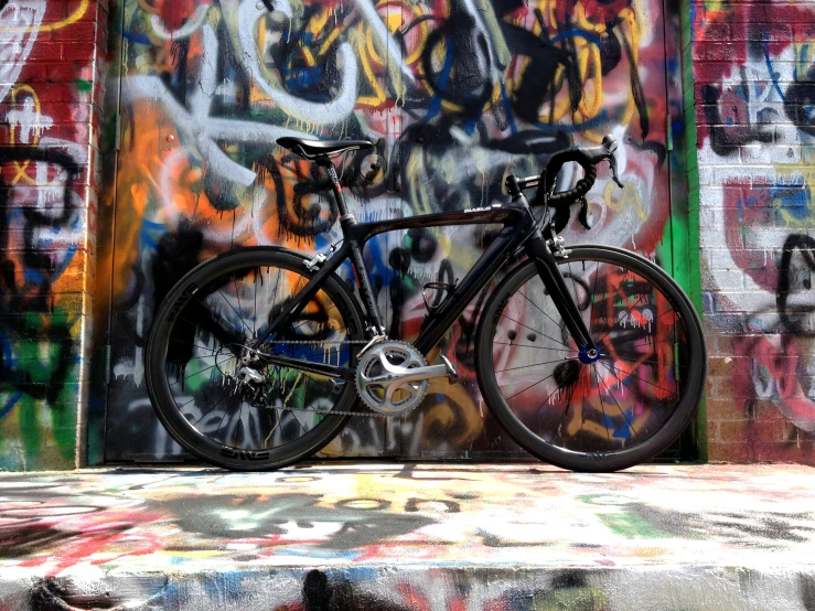the bicycle is standing in front of the graffiti covered wall