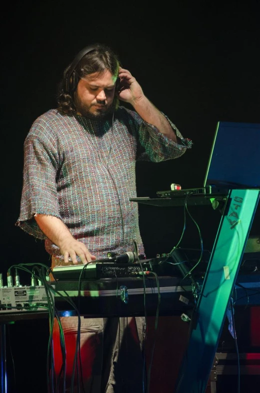 man at keyboard with headphones on listening to music