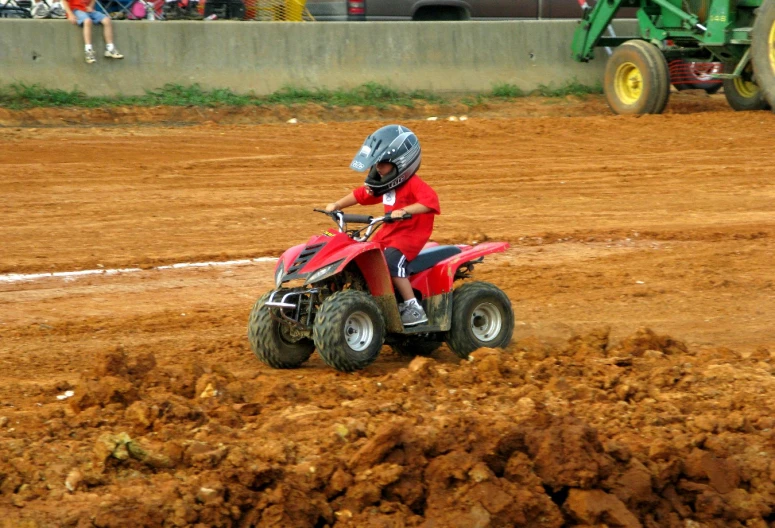 a boy on a red atv going through mud