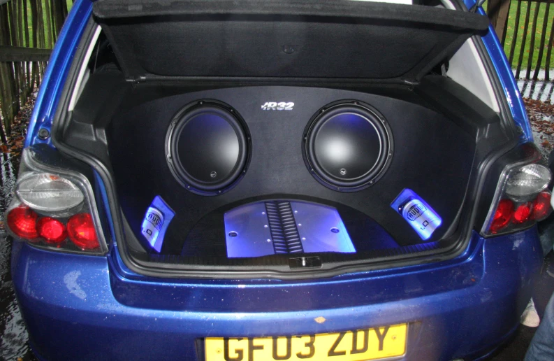 an open trunk of a small car filled with speakers