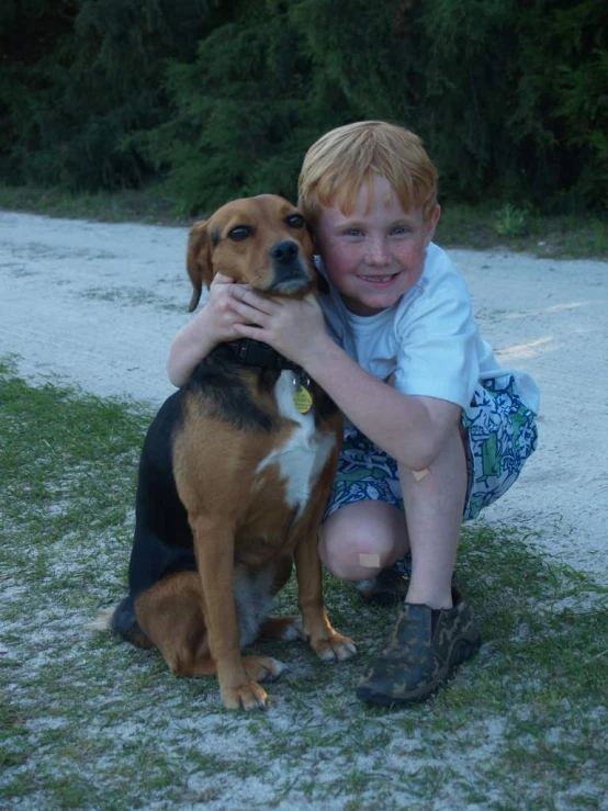 the boy is smiling and cuddling his dog