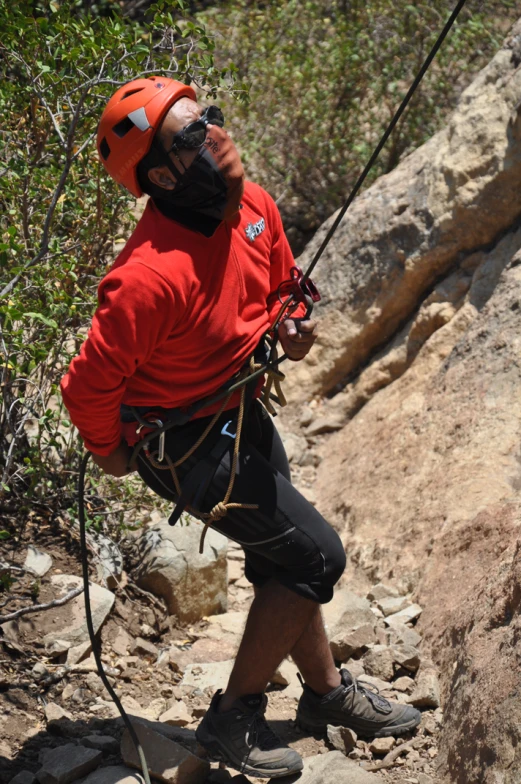 a man hanging on to the side of a cliff with a rope