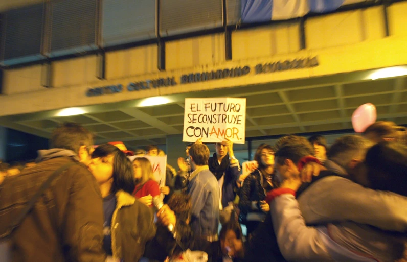 a crowd of people hold up signs