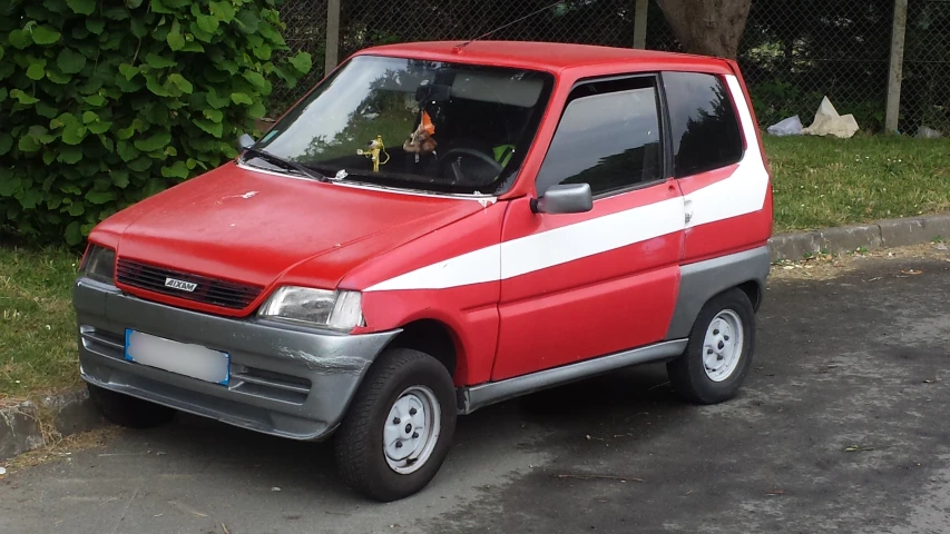 a red small car is parked in the parking lot