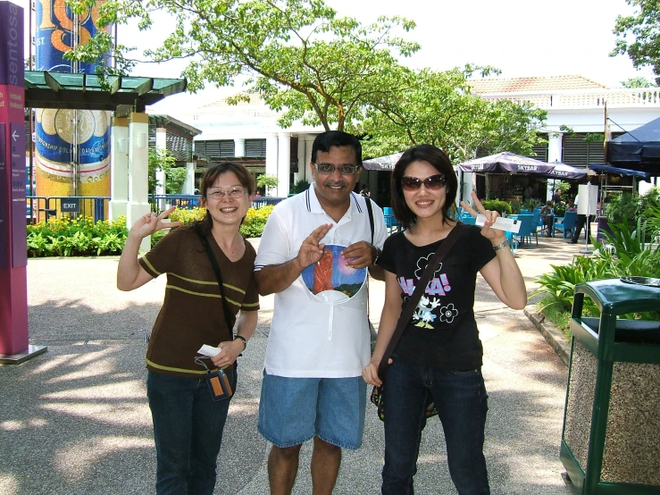 three people are posing while the one on the right gives a peace sign