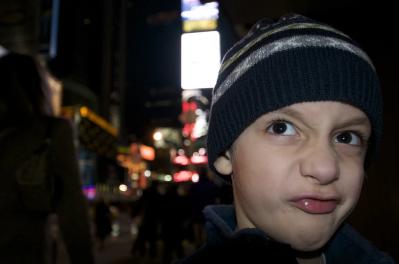 a boy making an obscene face on a busy city street at night