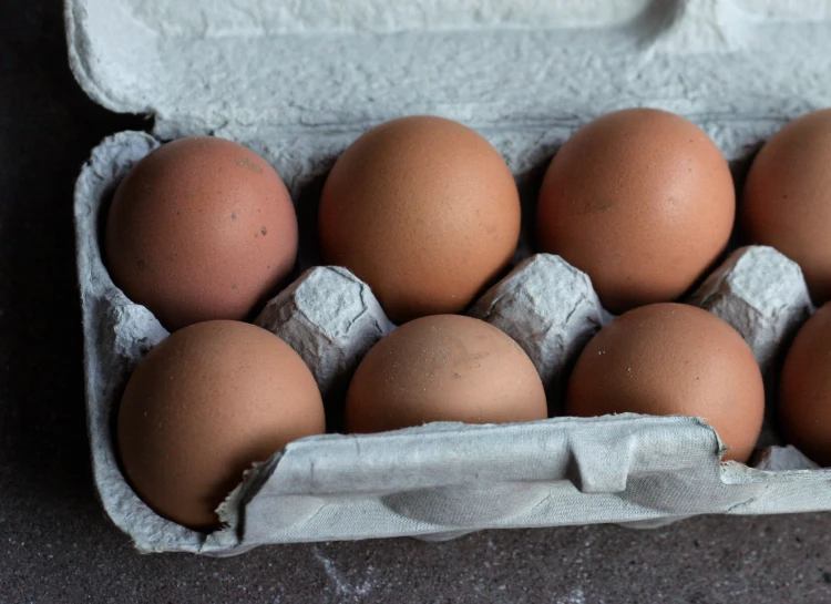 six brown eggs in a carton on a table