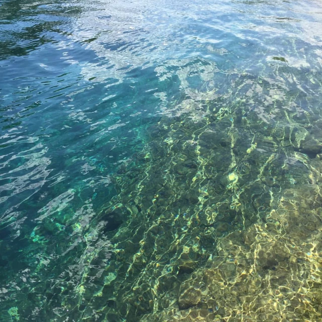 clear blue water over a sandy beach with sunlight