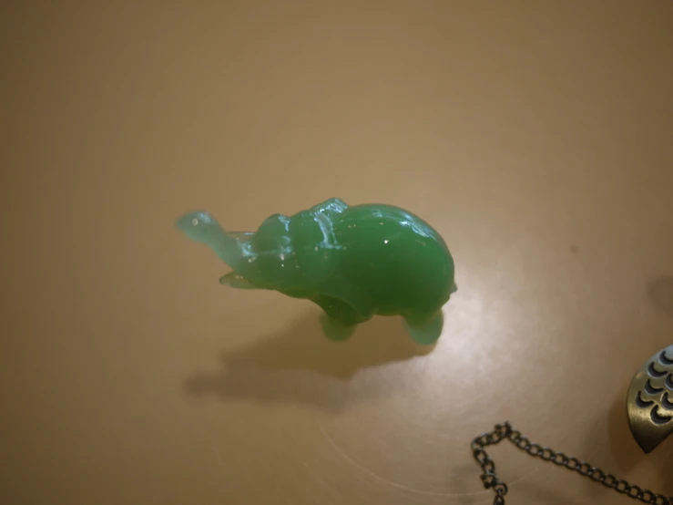 a green glass elephant keychain is on the table