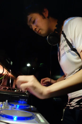 a dj wearing a light up white t - shirt is playing the music on turntables
