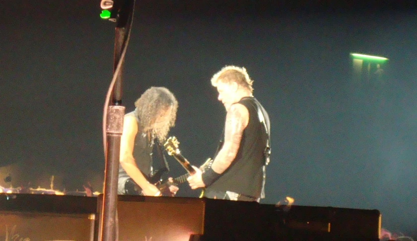 one man and the other woman is on a roof holding a microphone and playing guitar