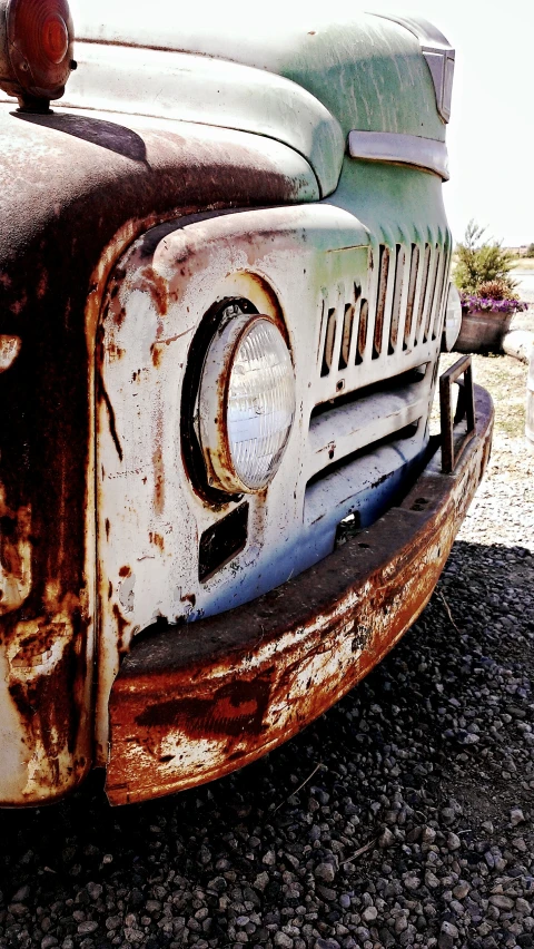 an old truck sitting in a yard near the sand