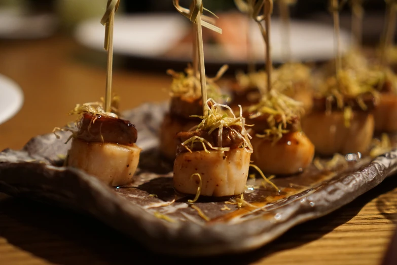 scallops are topped with seaweed and mustard on an olive tray