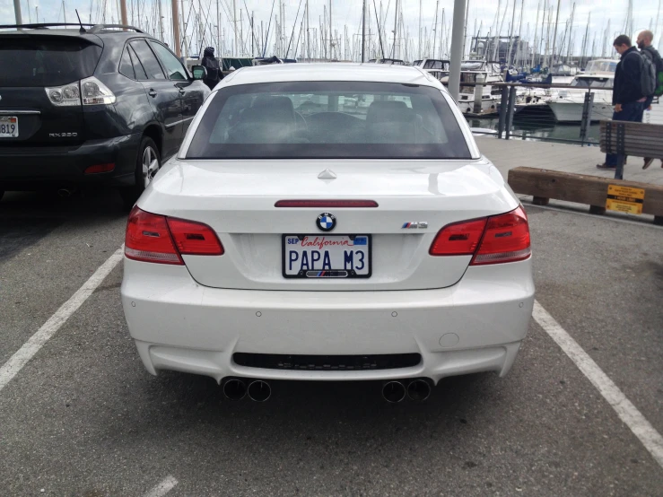 white bmw car parked in a parking lot near people walking around