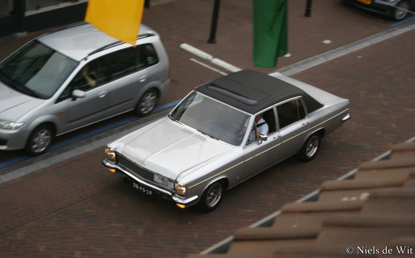 a silver car driving down a street next to a white truck