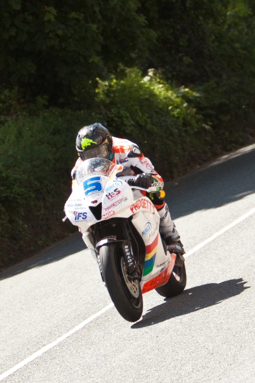 a man riding a white motorcycle on a paved road