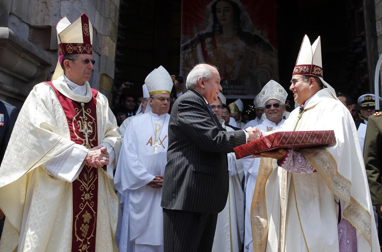 two priests shake hands as they prepare to perform the solemn