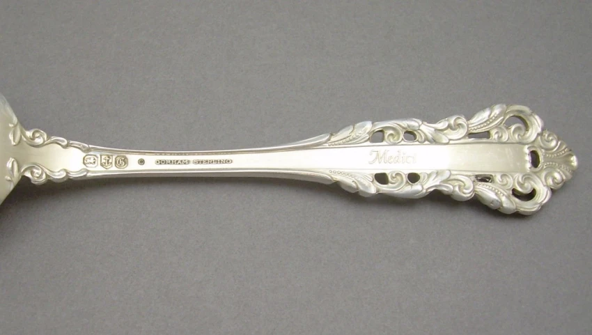 a large silver spoon with floral design and a circular handle