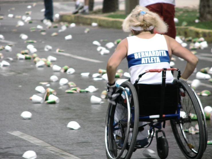 woman with a wheelchair looking down at broken cans on the street