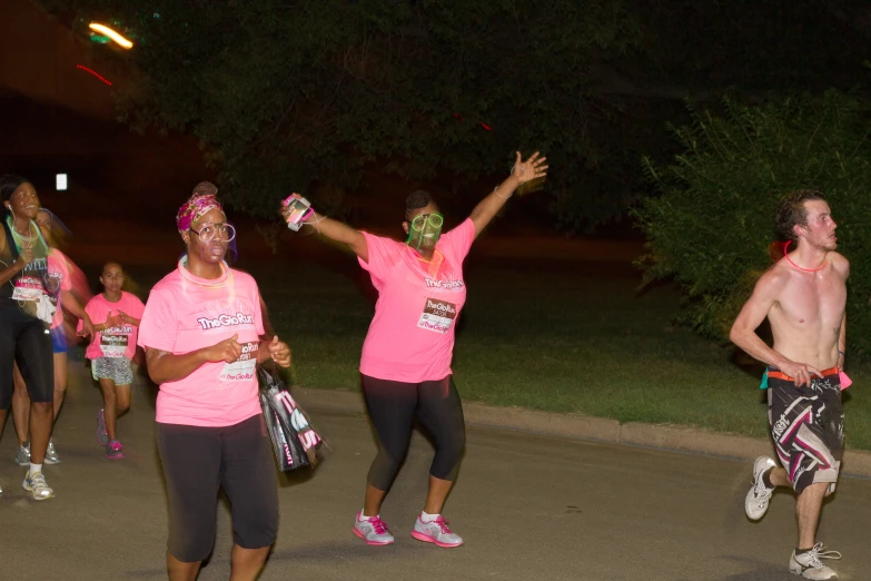 a group of people wearing pink running down a road