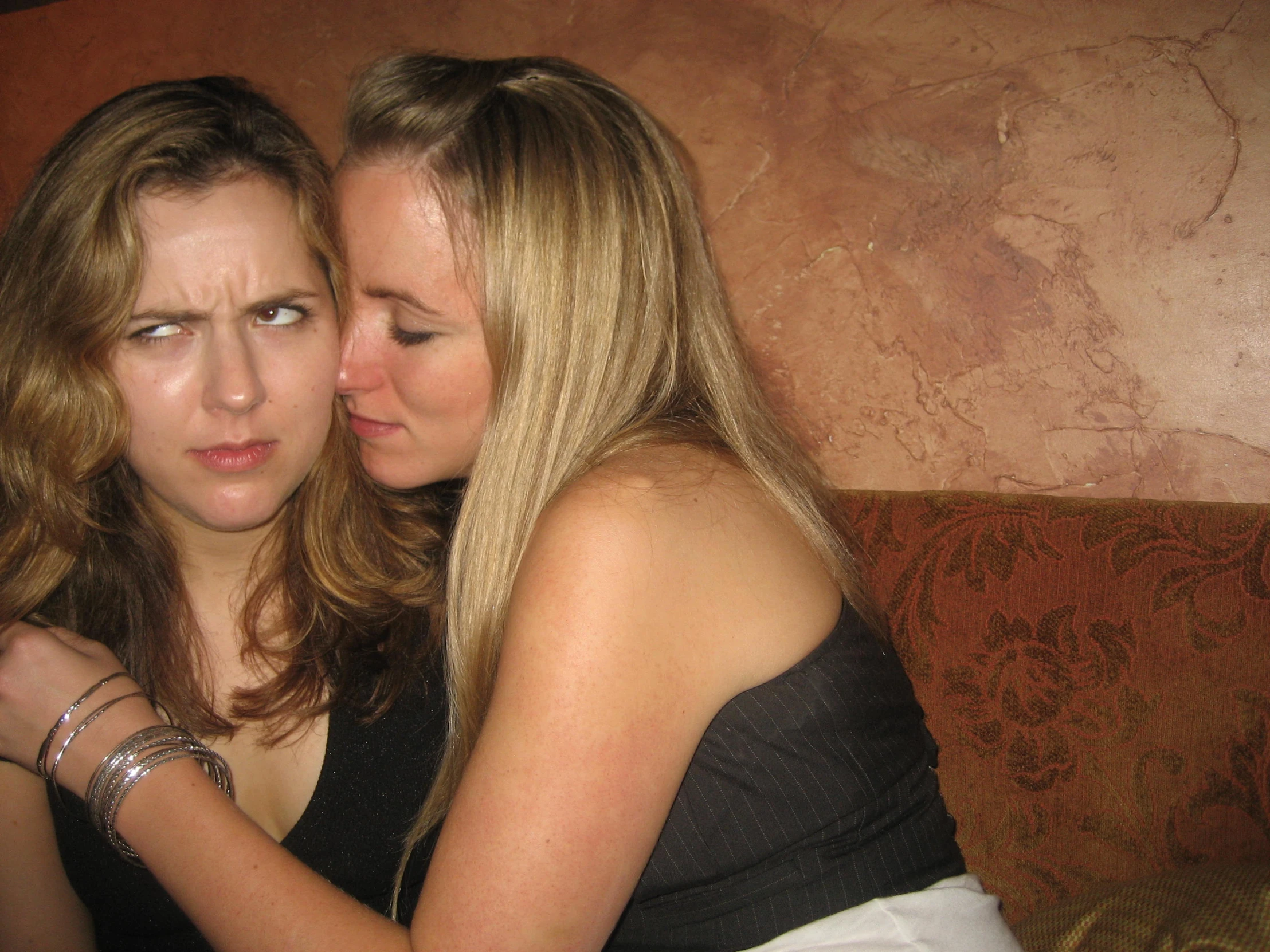 two women emcing each other on a couch