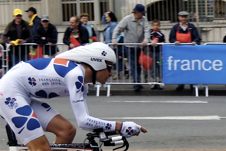 a male bicyclist is racing with an audience