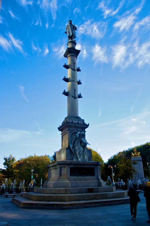 a large, tall statue stands in a park against the blue sky