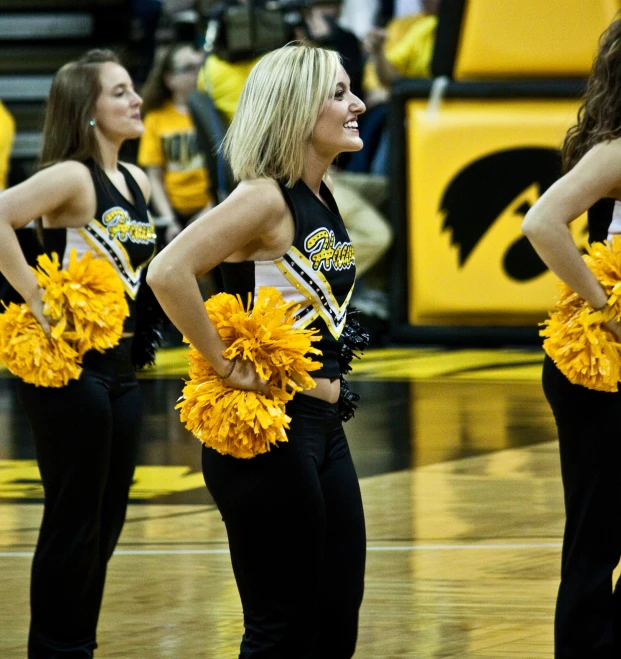 several women stand on the court with yellow pom poms