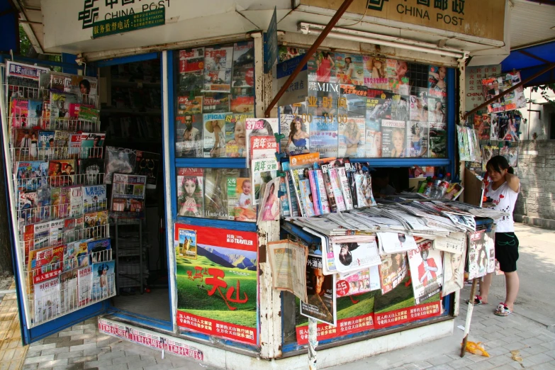 a man stands outside of a newspaper stand
