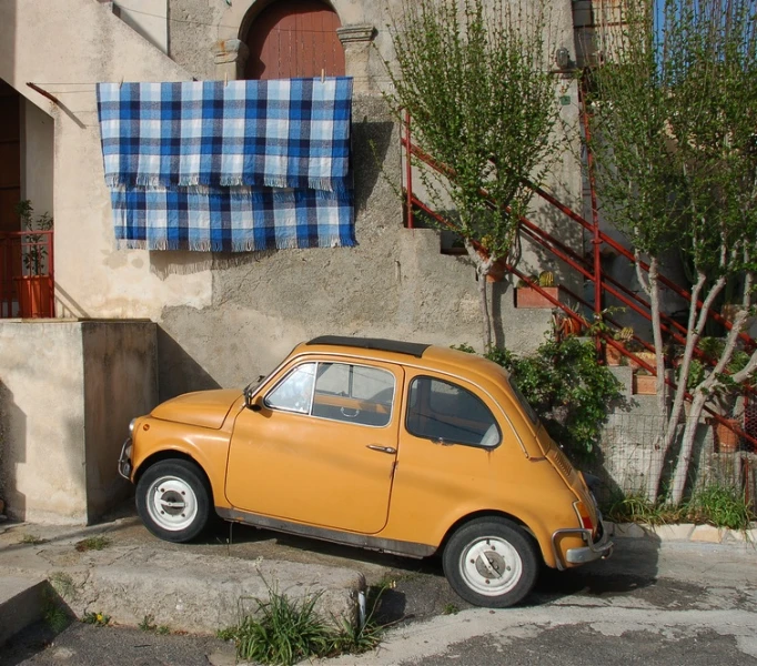 a small orange car parked in front of a building