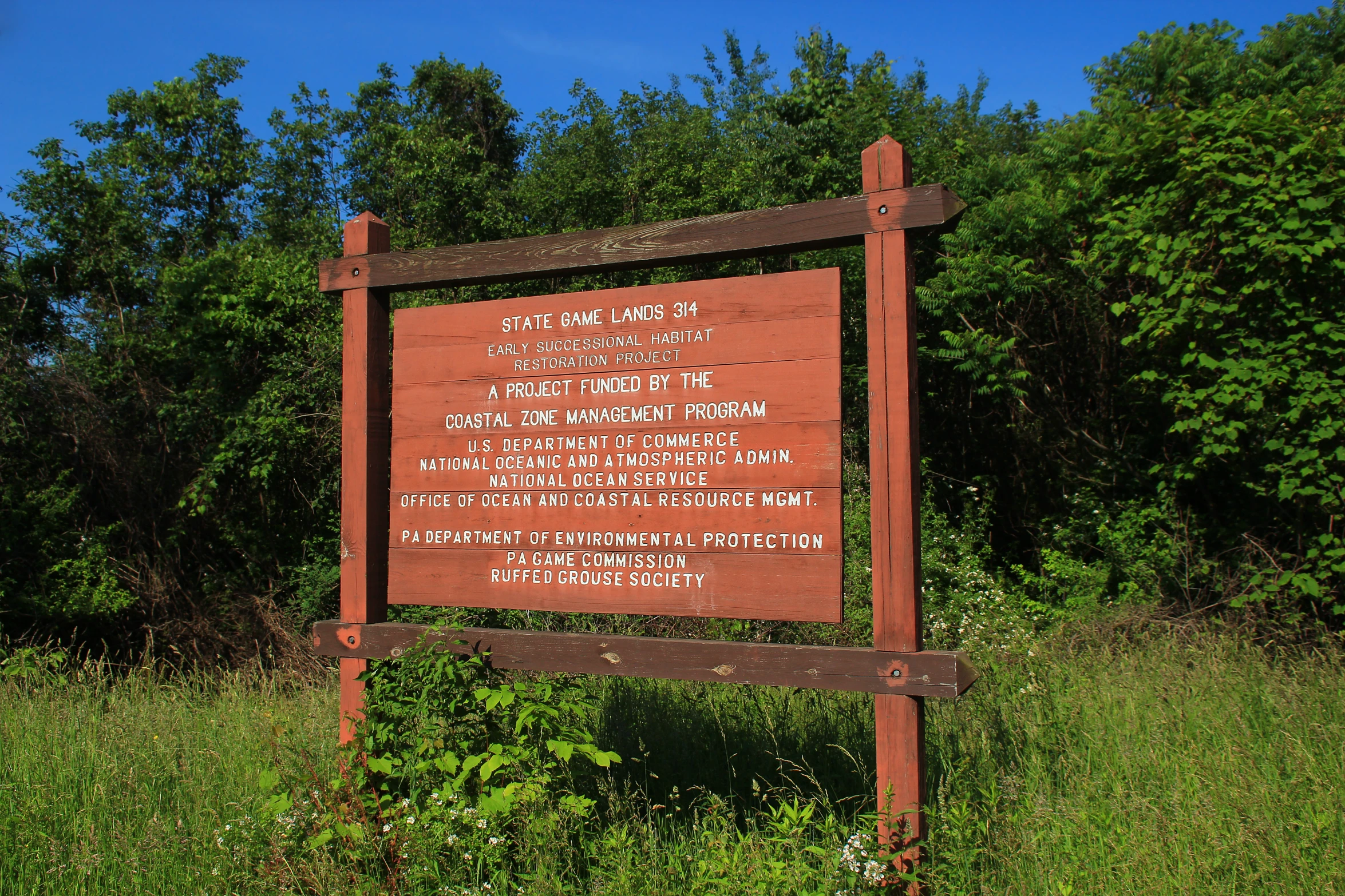 a sign is sitting in a field with green bushes