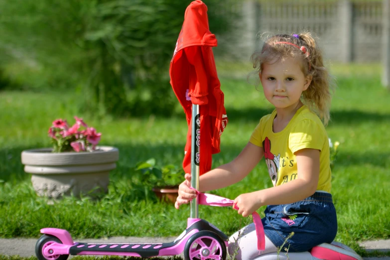 the little girl is sitting on the toy scooter