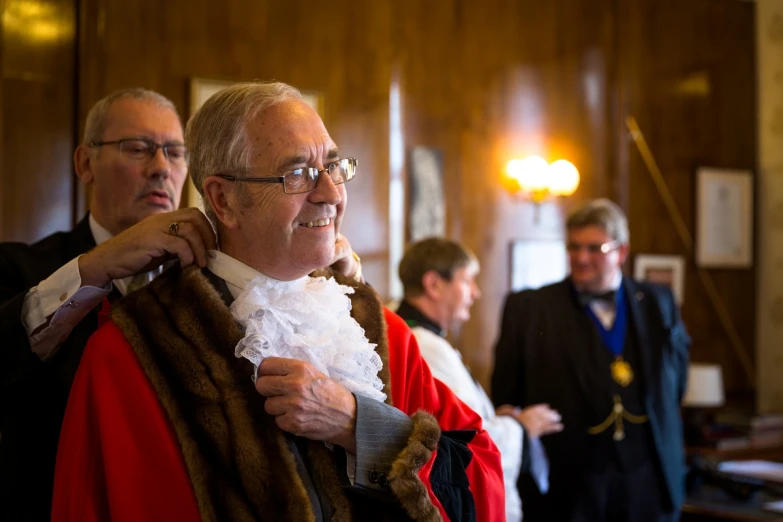 a man in a suit getting dressed up in a large robe