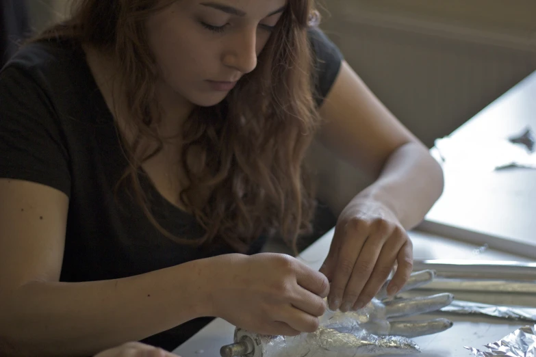 a woman is peeling up tinfoil onto soing