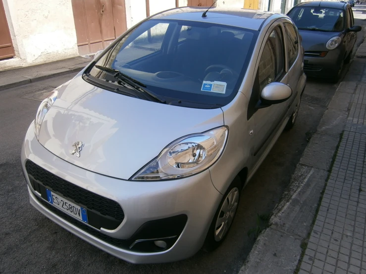 a silver smart car parked on the side of a street
