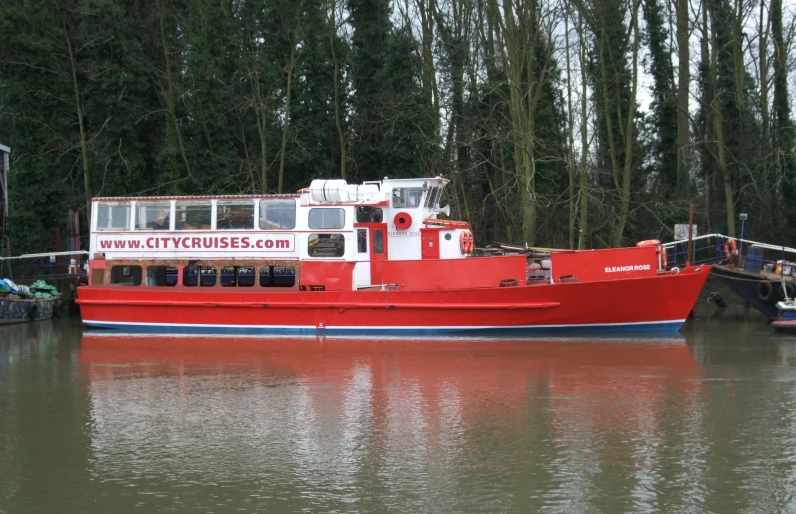 a large red boat sits parked at the dock