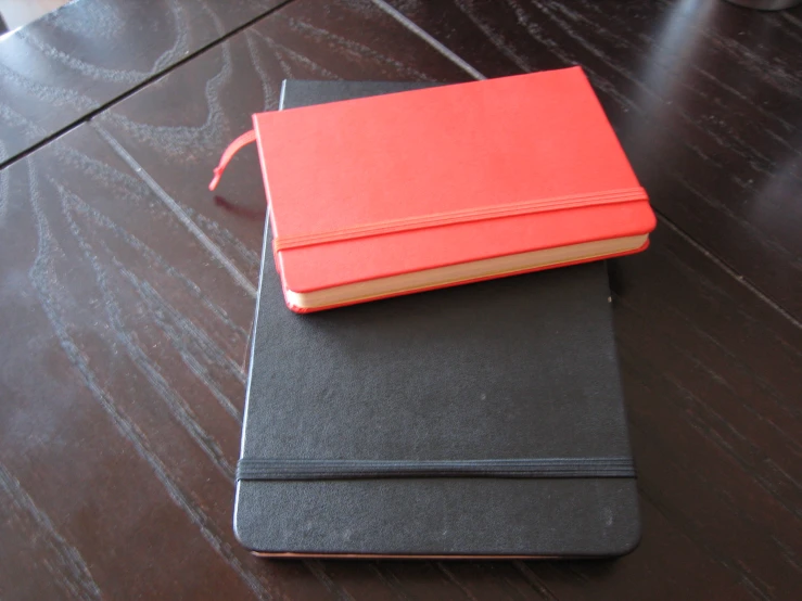 a black and a red book on a table