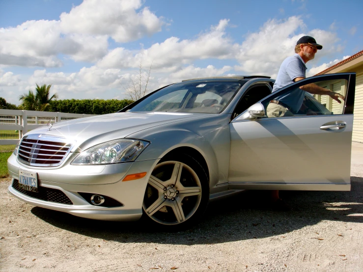 a man in a baseball cap standing at the open car door