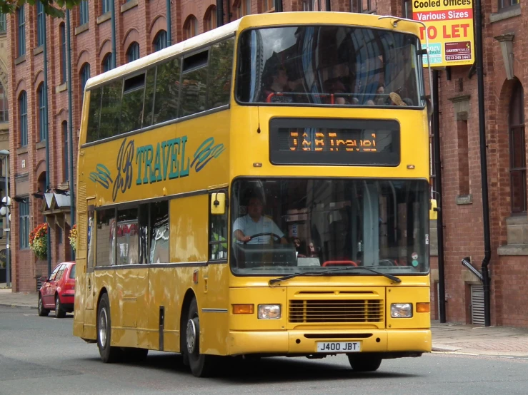 yellow double decker bus travelling down a city street