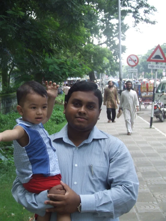 an indian man holding a child on a sidewalk