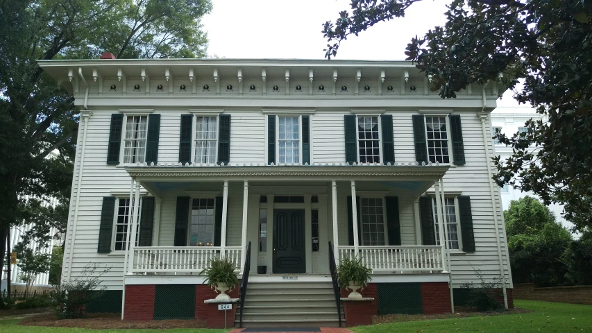 an old white house with shutters in the front