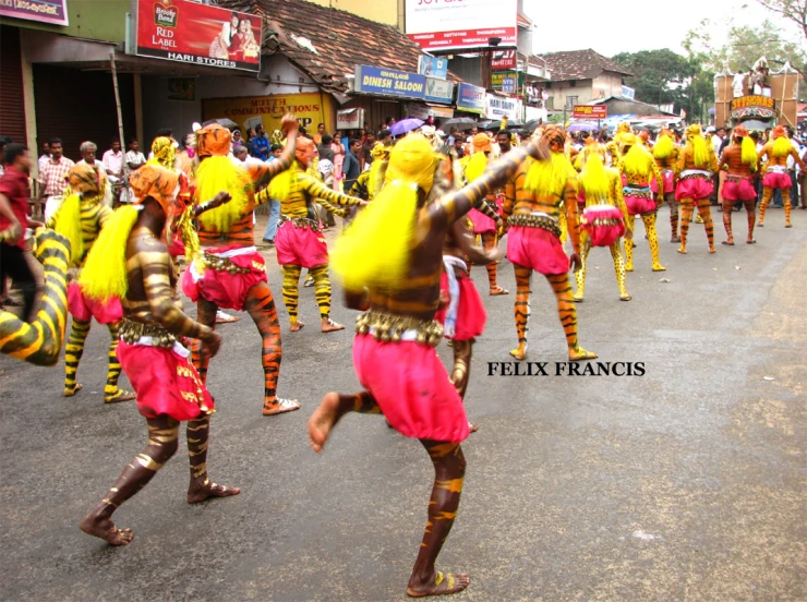 a large group of people dressed in brightly colored costumes are marching down the street