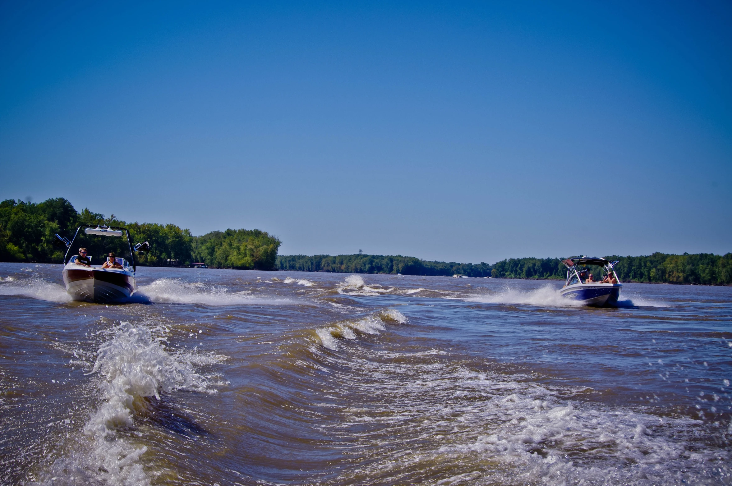 two boats are racing on the water near land