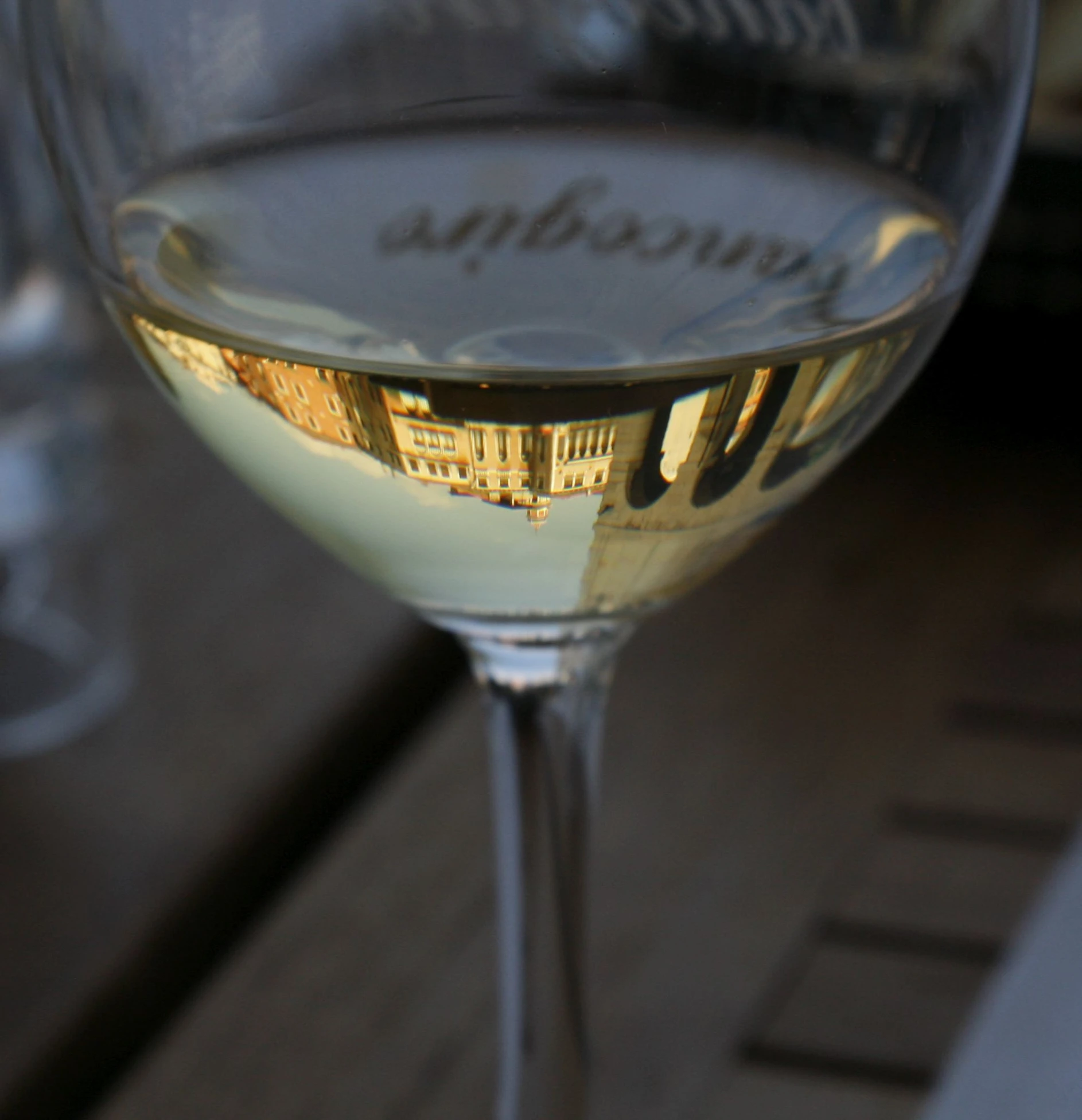 reflection of buildings in wine glass of white wine