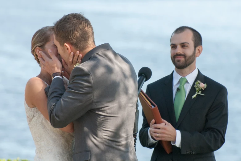 the newly husband kisses his wife while she stands at a microphone