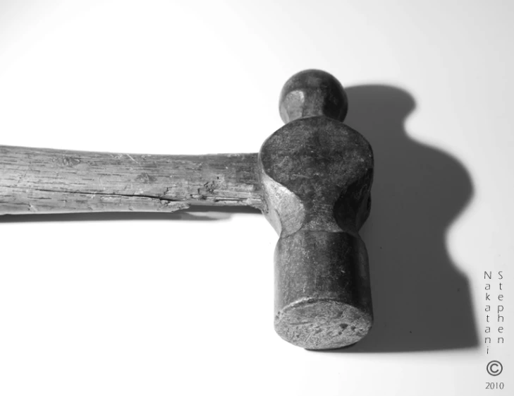 an old hammer with a wooden handle resting on a wall