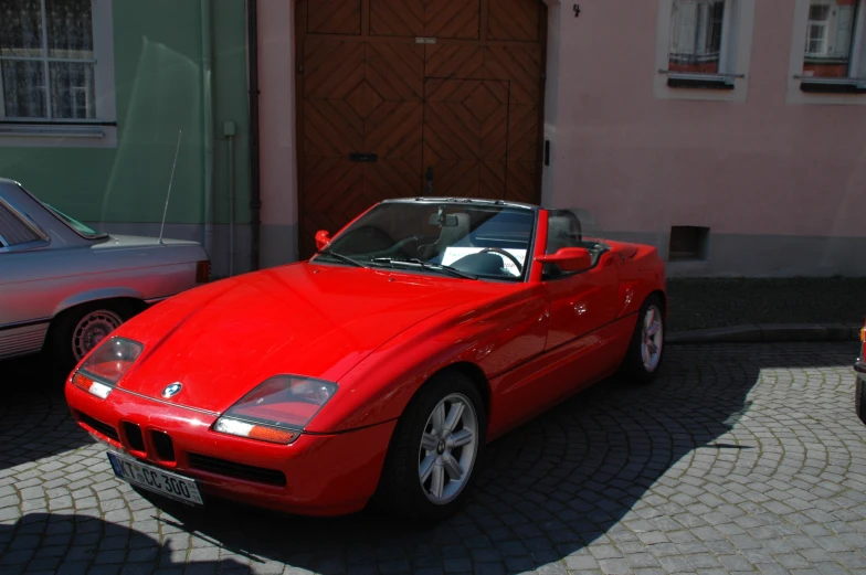 a red sports car with open top on brick street