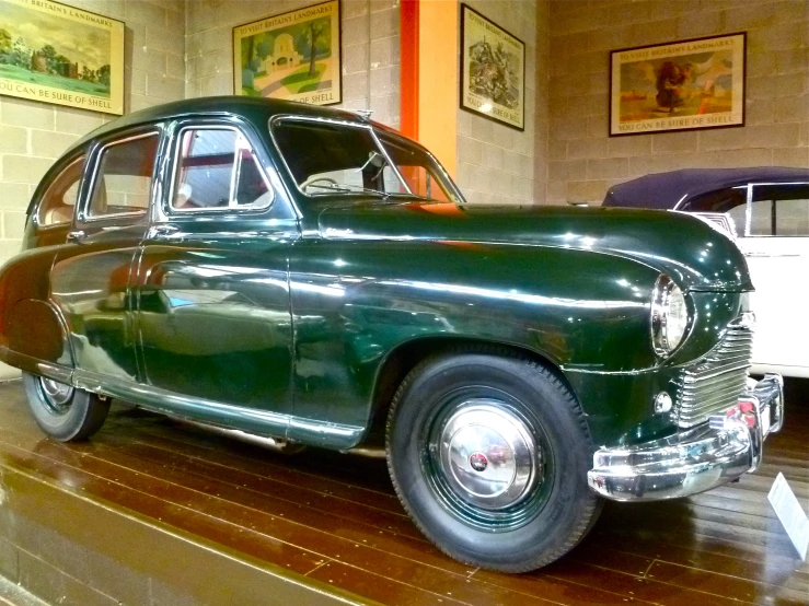 an antique green car in the museum with other cars