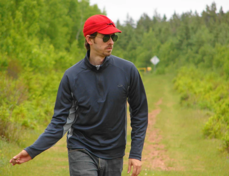 a man walking down a road with a red hat