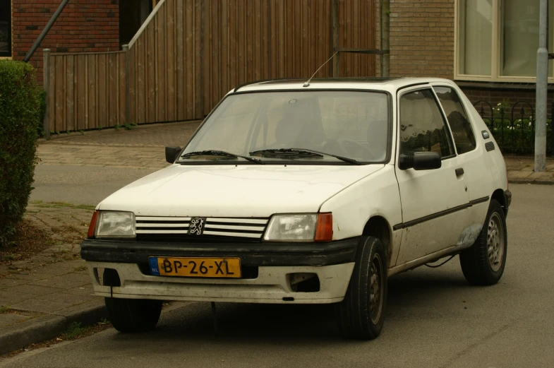 an old white car parked in the street near a building